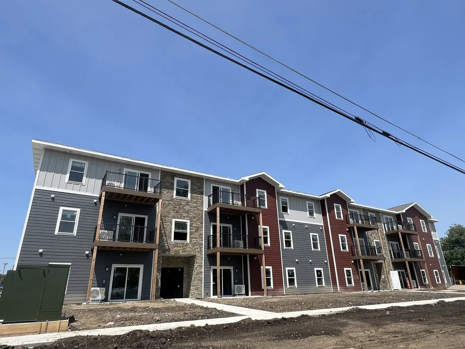 Three story apartment building with lap siding in several colors and stone, under construction